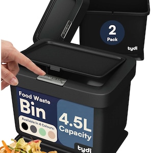 May include: A black 4.5L food waste bin with a push-to-open lid mechanism. The bin features a label stating Food Waste Bin, 4.5L Capacity, and Tydi branding. A second bin is visible in the background, indicating a 2 pack set. Food scraps are present.