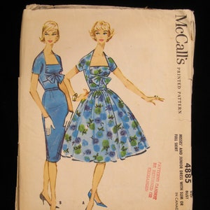 May include: Vintage McCall's sewing pattern for a dress with a full skirt. The pattern is for sizes 10 and includes instructions for a slim or full skirt. The pattern is printed on a white background with blue and green floral illustrations.