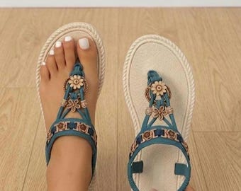 Sandalias planas de mujer de estilo bohemio en color verde con detalles florales y suela con efecto de cuerda.