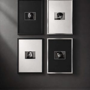 Può includere: Un set di quattro cornici rettangolari da parete disposte a griglia. Due cornici sono nere e due sono argentate. Ogni cornice contiene un passe-partout bianco che circonda una piccola fotografia ritratto in bianco e nero centrata.