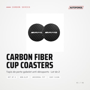 May include: Two circular black carbon fiber cup coasters featuring the white AMG logo. The text CARBON SERIES and AUTOFORGE appear at the top, with CARBON FIBER CUP COASTERS, Tapis de porte-gobelet anti-dérapants, and Set of 2 below.