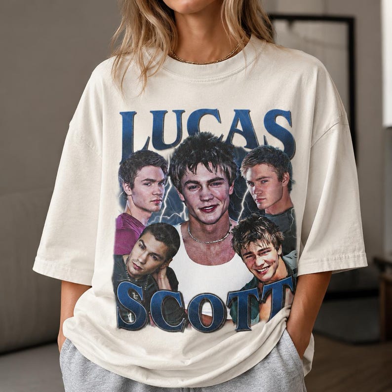 Puede incluir: Una camiseta de manga corta color blanco hueso con un estampado gr&aacute;fico del personaje Lucas Scott de One Tree Hill. El dise&ntilde;o incluye cinco retratos diferentes del personaje con el texto LUCAS SCOTT en letras azules grandes.