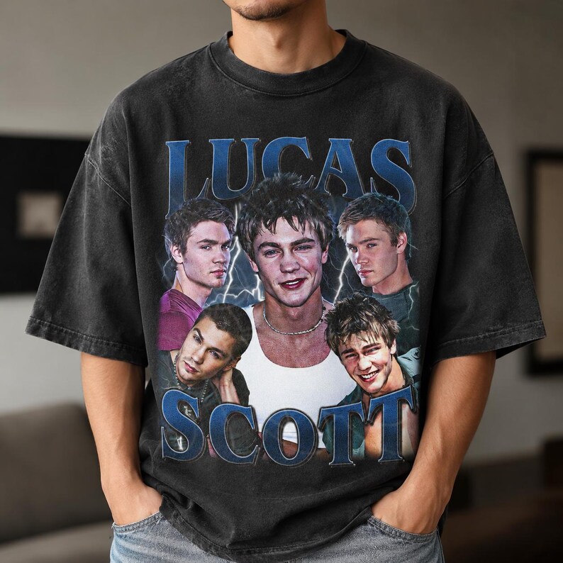 Puede incluir: Una camiseta de manga corta en color gris carb&oacute;n con un estampado gr&aacute;fico de Lucas Scott de One Tree Hill. El dise&ntilde;o incluye el nombre LUCAS SCOTT en letras azules grandes y cinco retratos fotogr&aacute;ficos diferentes del personaje.