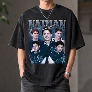 Puede incluir: Una camiseta negra de manga corta con un estampado gr&aacute;fico del personaje Nathan Scott de One Tree Hill. El dise&ntilde;o incluye varias im&aacute;genes del personaje con una chaqueta universitaria, el nombre NATHAN SCOTT y rayos azules.