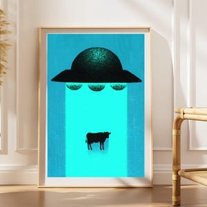 May include: A framed vertical art print featuring a dark, textured UFO hovering against a bright cyan background. A beam of light extends downward from the craft, illuminating a small, black silhouette of a cow standing in the center of the beam.