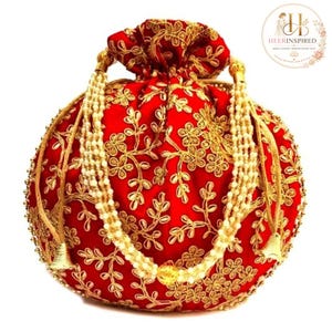Puede incluir: Un bolso redondo de color rojo con cierre de cordón que presenta un intrincado bordado floral dorado en toda la tela. El bolso incluye un asa hecha de múltiples hilos de perlas artificiales color crema y detalles metálicos dorados.