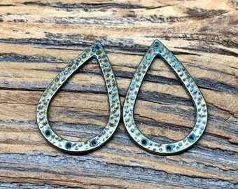 May include: Two teardrop-shaped metal charms with a textured surface and a turquoise blue finish. The charms have a hole at the top and three smaller holes around the edge.