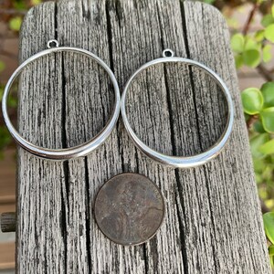 K&ouml;nnte beinhalten: Zwei silberfarbene Metallringe mit einer kleinen Schlaufe oben. Die Ringe sind etwa so gro&szlig; wie ein 1-Cent-St&uuml;ck.