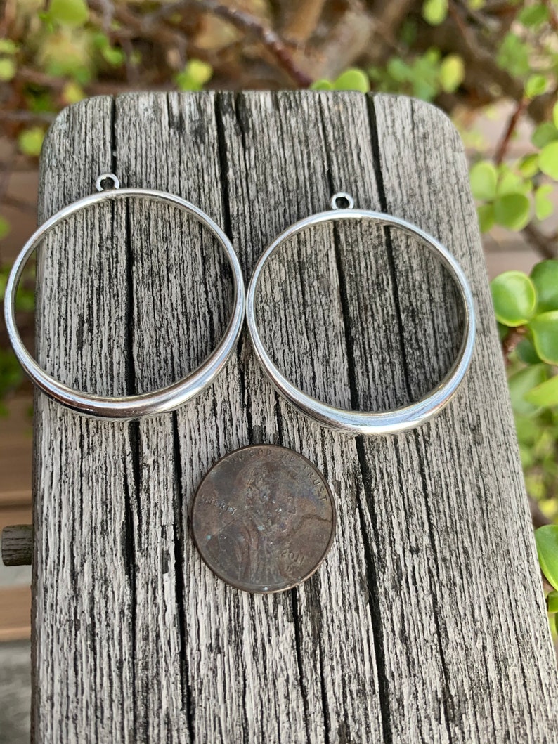 K&ouml;nnte beinhalten: Zwei silberfarbene Metallringe mit einer kleinen Schlaufe oben. Die Ringe sind etwa so gro&szlig; wie ein 1-Cent-St&uuml;ck.
