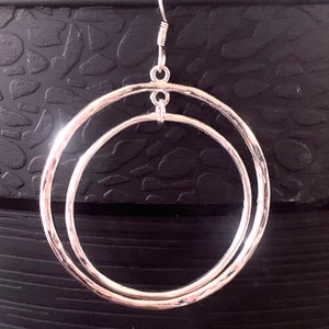 Puede incluir: Pendientes de aro de plata con un dise&ntilde;o de doble c&iacute;rculo. Los pendientes tienen una textura martillada y un estilo simple y elegante.
