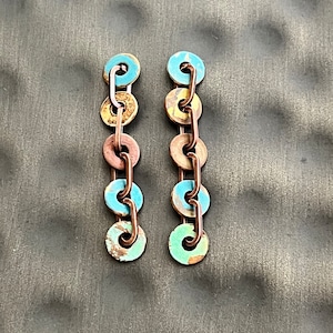 May include: A pair of long, dangling earrings with a chain of copper and blue and green enamel circles.