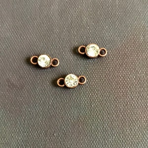 May include: Three small, clear crystal connectors with copper-toned metal loops. The connectors are perfect for adding a touch of sparkle to jewelry projects.