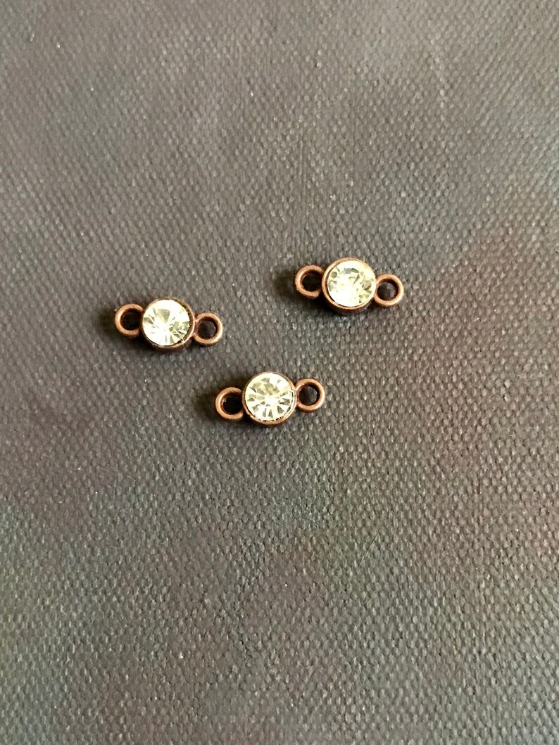 May include: Three small, clear crystal connectors with copper-toned metal loops. The connectors are perfect for adding a touch of sparkle to jewelry projects.