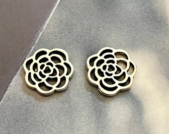 Könnte beinhalten: Zwei silberne Metall-Anhänger in Blumenform mit einem filigranen, komplizierten Design.