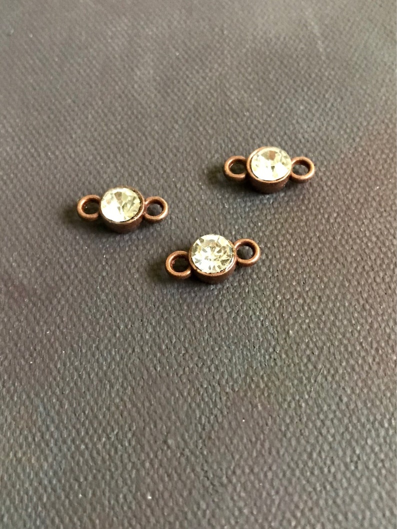 May include: Three copper-toned connector charms with clear crystal rhinestones. Each charm has two loops for attaching to jewelry.