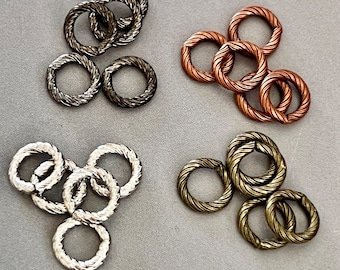 Könnte beinhalten: Vier Sätze mit silbernen, kupfernen, goldenen und schwarzen Sprungringen. Jeder Satz enthält fünf Sprungringe mit einem gedrehten Seil-Design.
