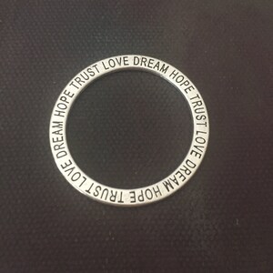 May include: A silver ring with the words "HOPE TRUST LOVE DREAM" engraved around the band.