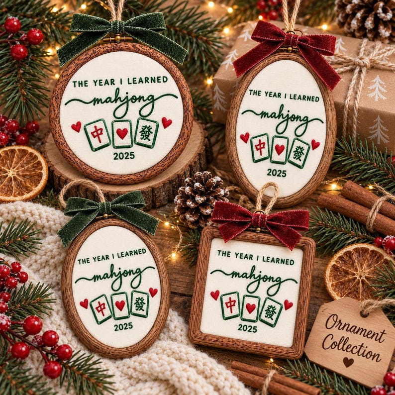 May include: Four wooden framed ornaments featuring white fabric with the text THE YEAR I LEARNED mahjong 2025, embroidered mahjong tiles, and red hearts. Each ornament is topped with a velvet bow in either dark green or deep red and a jute loop.