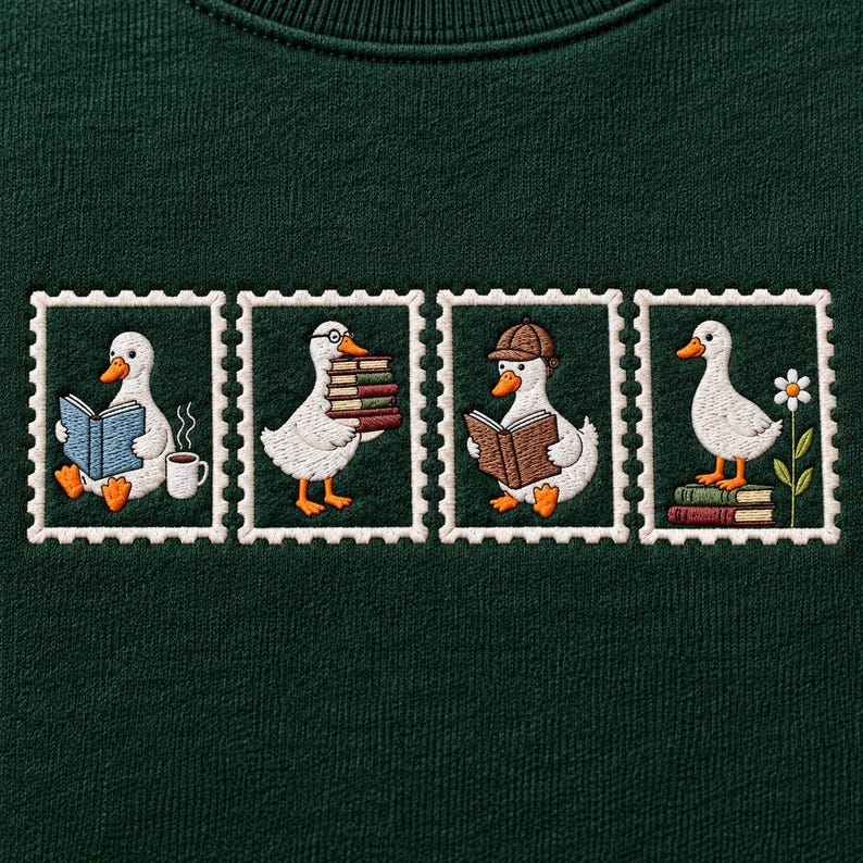 May include: A dark green sweatshirt featuring four embroidered stamp-shaped designs. Each frame depicts a white duck with orange feet and a beak, engaged in various activities including reading books, holding a stack of books, and standing near a flower.