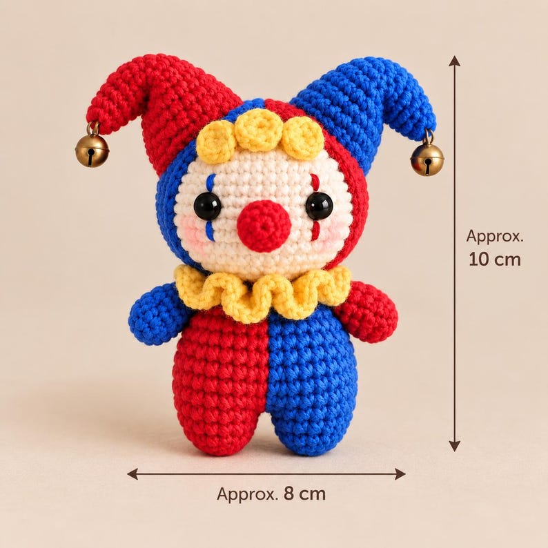 May include: A crocheted clown doll with a red and blue jester hat featuring two small brass bells. The doll has a cream-colored face, a red nose, black eyes, and a yellow ruffled collar. It measures approximately 10 cm in height and 8 cm in width.