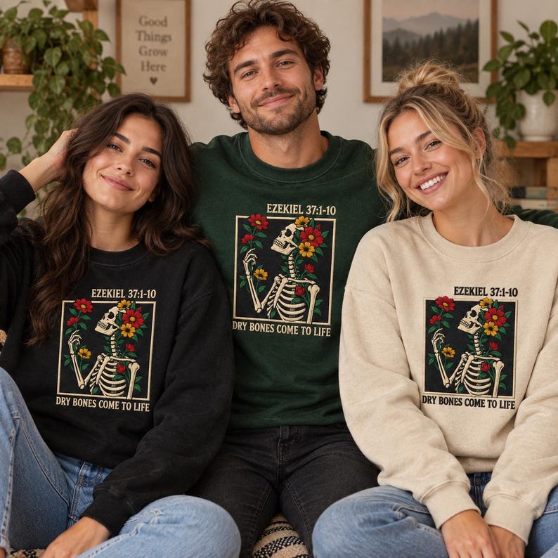 May include: Three crewneck sweatshirts in black, dark green, and beige, each featuring a graphic of a skeleton surrounded by red and yellow flowers. The text "EZEKIEL 37:1-10" and "DRY BONES COME TO LIFE" is printed above and below the illustration.