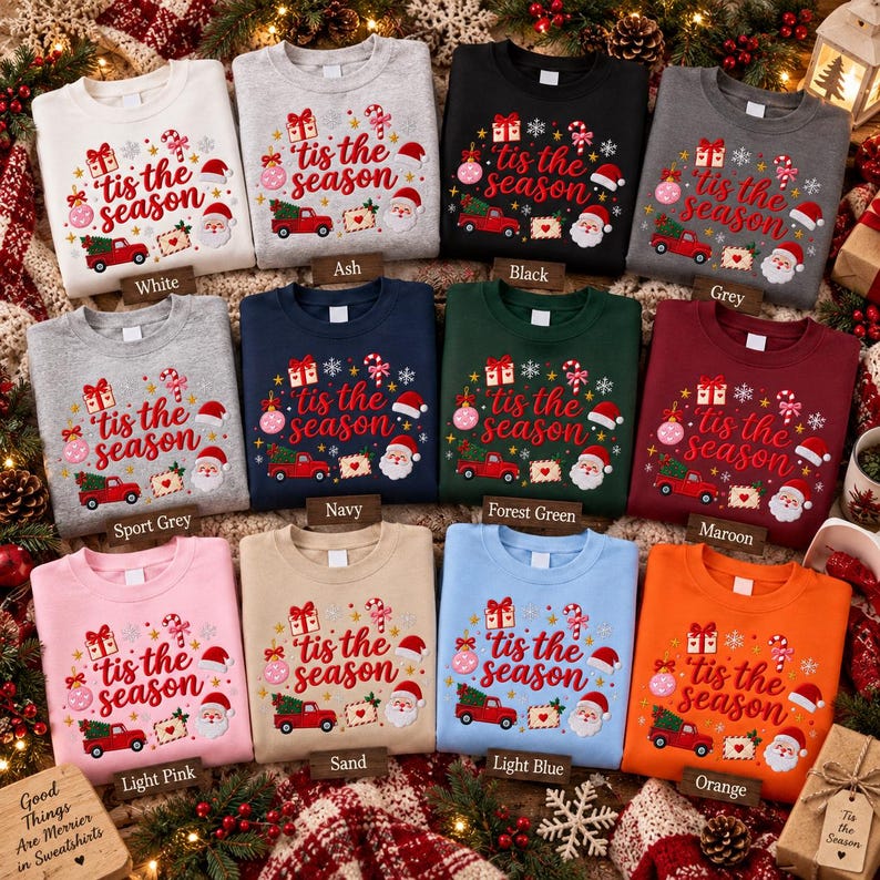 May include: A collection of twelve crewneck sweatshirts in various colors, each featuring a festive graphic with the text 'tis the season' surrounded by illustrations of a red truck, Santa Claus, gift boxes, candy canes, and snowflakes.