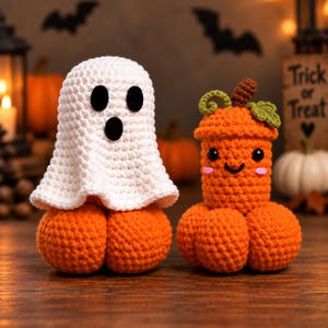 May include: Two handmade crochet figures. One is a white ghost with black oval eyes and a mouth sitting on an orange pumpkin base. The other is an orange pumpkin with a green stem and leaf, black eyes, a small smile, and pink cheeks.