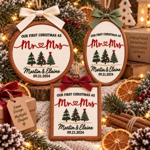 May include: Three embroidered ornaments in round, oval, and square wooden frames. Each features the text "OUR FIRST CHRISTMAS AS Mr & Mrs", the names "Martin & Elaine", the date "09.21.2024", and three green Christmas trees with red accents.