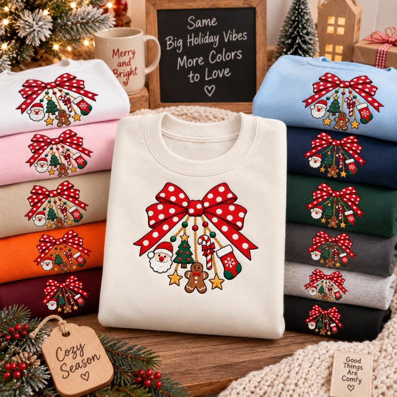 May include: A collection of crewneck sweatshirts in various colors, each featuring a graphic of a large red polka-dot bow with hanging Christmas ornaments including Santa, a tree, a candy cane, a gingerbread man, and a stocking.