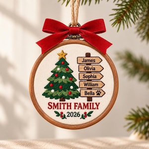 May include: A round wooden embroidery hoop ornament featuring a stitched Christmas tree with a yellow star, a signpost with the names James, Olivia, Sophia, William, and Bella, the text SMITH FAMILY 2026, and a red velvet bow with a jute hanging cord.