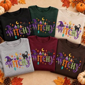 May include: A collection of six crewneck sweatshirts in black, dark green, beige, gray, maroon, and brown. Each features a graphic with the text WITCHY, a purple witch hat, a black cat, colorful potion bottles, a crescent moon, and stars.
