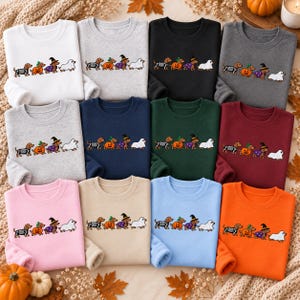 May include: A collection of twelve crewneck sweatshirts in various colors, each featuring a graphic of four dachshunds in Halloween costumes: one as a skeleton, one inside a pumpkin, one as a witch, and one dressed as a ghost.