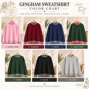 May include: A color chart for a gingham sweatshirt featuring seven options: light pink, maroon, blue, green with red trim, green, black, and ash gray. Each sweatshirt has a mock neck and cuffs with a gingham pattern. The text reads GINGHAM SWEATSHIRT COLOR CHART.