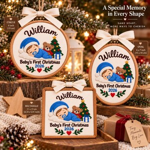 May include: Three wooden embroidery hoop ornaments in circle, oval, and square shapes. Each features embroidered text 'William', 'Baby's First Christmas 2026', a sleeping baby in blue, a teddy bear, and a Christmas tree. Each has a cream ribbon bow.