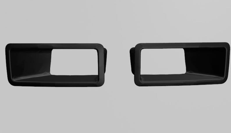 May include: Two identical matte black rectangular automotive exhaust trim bezels with rounded corners and hollow centers. These components feature a smooth, solid finish and a wide, open design intended for vehicle exterior installation.