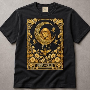 Könnte beinhalten: Ein schwarzes Kurzarm-T-Shirt mit einem goldenen Grafikdruck eines Bienenstocks in einer Mondsichel, umgeben von Bienen und Blumenranken. Der Text LUNA MELLIS ist am unteren Rand des rechteckigen Rahmendesigns aufgedruckt.