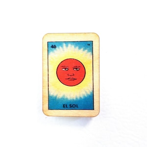 May include: A vintage-style Loteria card with a red sun face with a yellow halo. The card is numbered 46 and the text "EL SOL" is printed below the sun.
