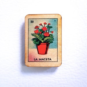 May include: A wooden card with a red flower pot and red flowers. The card is labeled "52" and "LA MACETA" in black text.