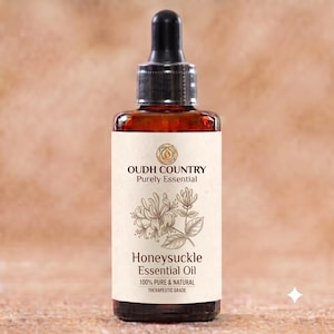 May include: A dark amber glass bottle with a black dropper cap containing Honeysuckle Essential Oil. The cream-colored label features the text OUDH COUNTRY Purely Essential, a botanical illustration of honeysuckle, and 100% PURE & NATURAL.