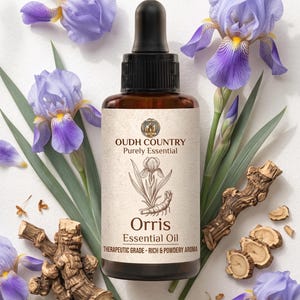 Op de afbeelding: Een bruine glazen fles met een zwarte druppeldop met Orris etherische olie. Het etiket bevat de tekst OUDH COUNTRY Purely Essential, een illustratie van een irisbloem en de woorden Therapeutic Grade - Rich & Powdery Aroma.