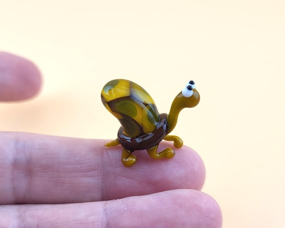 A tiny lampwork-glass turtle sculpted by hand — the kind of miniature you pick up, turn over, and can't put down.