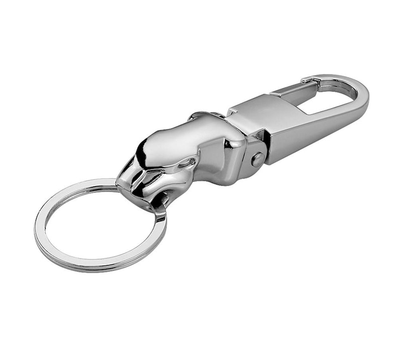 May include: A polished silver-tone metal keychain featuring a stylized jaguar head ornament. The design includes a sturdy spring-loaded lobster clasp mechanism connected to a circular split ring, providing a secure way to organize keys.