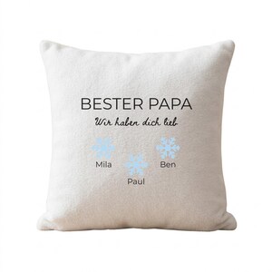 May include: A white square throw pillow featuring the black text BESTER PAPA and Wir haben dich lieb. Below the text are three light blue snowflake icons, each labeled with the names Mila, Paul, and Ben in black font on the pillow surface.