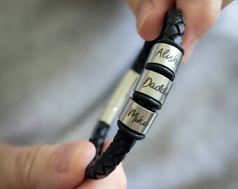 May include: Black leather bracelet with three silver beads engraved with the names Alisha, Daddy, and Mika.