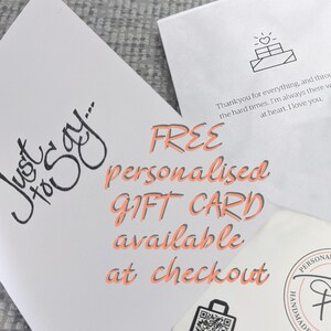 May include: A white card with the text "Just To Say..." in black cursive writing. The card also features the text "FREE personalised GIFT CARD available at checkout" in pink text. A small black and white icon of a stack of boxes with a heart on top is in the upper right corner of the card.