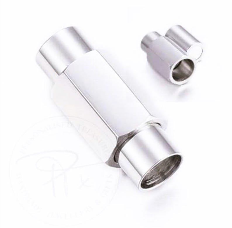 K&ouml;nnte beinhalten: Ein Paar gl&auml;nzende, silberfarbene Metallverschl&uuml;sse. Einer ist gr&ouml;&szlig;er und sechseckig, mit zylindrischem Ende. Der andere ist kleiner und zylindrisch. Die Verschl&uuml;sse sind vor wei&szlig;em Hintergrund platziert.