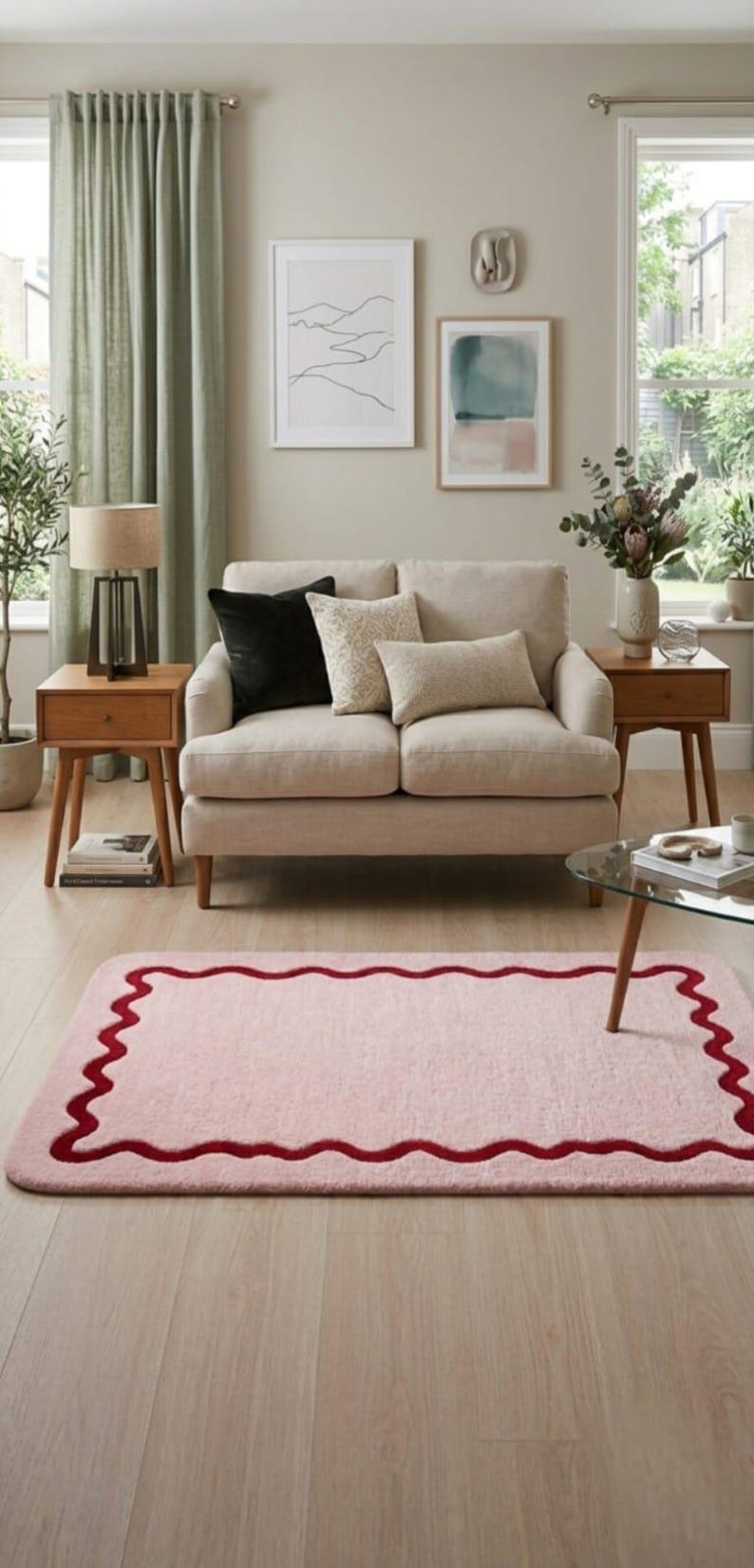 May include: A rectangular area rug featuring a soft light pink base color with a dark red scalloped border design. The rug has rounded corners and a plush, textured surface, positioned on a light-colored wooden floor in a living room setting.