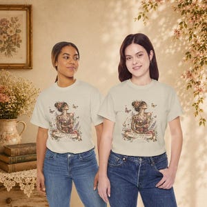 May include: A cream-coloured short-sleeve t-shirt featuring a detailed graphic of a person in a yoga pose surrounded by flowers and butterflies. The text "Have you tried yoga? I heard it helps" is printed in a banner at the bottom of the illustration.