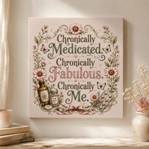 Op de afbeelding: Vierkante canvas print met de tekst "Chronically Medicated, Chronically Fabulous, Chronically Me". Het kunstwerk bevat bloemen- en vlinderaccenten, samen met illustraties van medicijnflesjes, pillen en een strik.