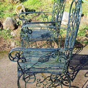 May include: Two ornate metal chairs with a green painted finish. The chairs have a decorative scroll design and are made of wrought iron.